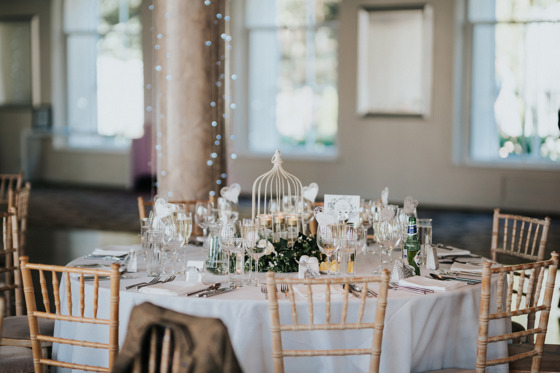 Wedding meal setup with chiavari chairs and bird cage decor on table